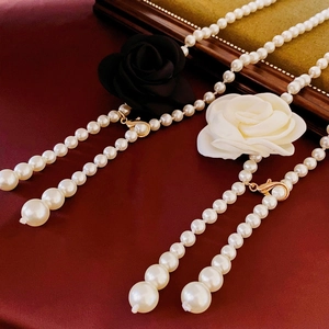 Détail de colliers en perles avec fleurs en tissu noir et blanc sur fond rouge élégant