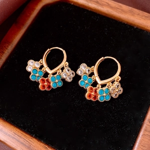 Detail of 18K gold-plated hoop earrings with floral pendants and colorful gemstones
