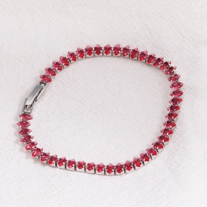 Detailed close-up of marquise-cut red crystals on silver-plated knotted tennis bracelet