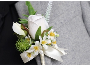 Detail of white rose boutonniere on grey suit lapel with beige silk ribbon bow