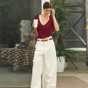 Detailed view of women's dark red V-neck knit top with white high-waisted trousers