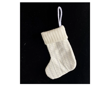 Detailed view of white knitted Christmas stocking with cable pattern and hanging loop