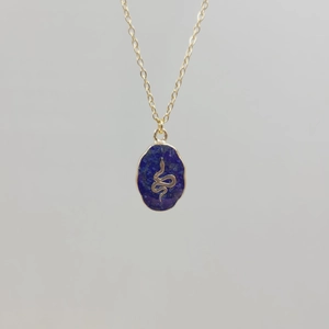 Macro detail of gold necklace featuring oval lapis lazuli pendant with a gold snake motif