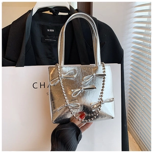 Detail of silver metallic pleated handbag with bow accents and elegant chain strap