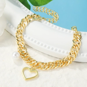 Detailed view of golden chain bracelet with hollow heart charm and white faux pearl detail