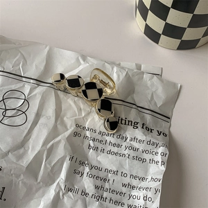 Detail of checkered hair claw clip with golden base and circular black and white patterns