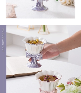 Detail of white ceramic bow goblet with petal-shaped rim held by a hand in a cozy setting