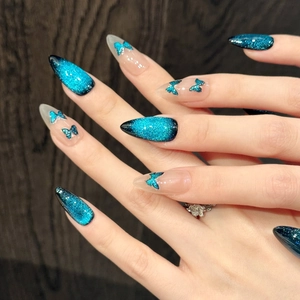 Detailed view of dark blue cat-eye press-on nails with 3D butterfly charms and glitter