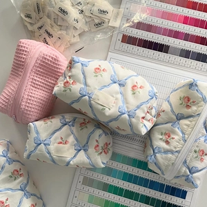 Flat lay of pink waffle cosmetic bags with blue bow patterns and brand labels