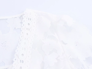 Close-up of white floral lace texture with hollow embroidery on a V-neck dress