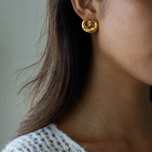 Close-up of gold pretzel twist earrings made of stainless steel on a female model