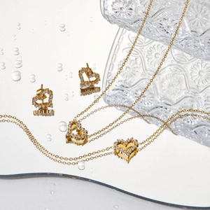 Golden heart jewelry set with clear zircon on water droplet reflective surface