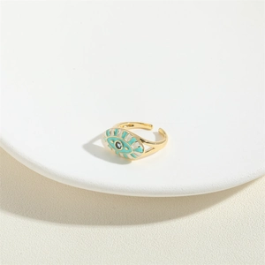 Adjustable golden evil eye ring with turquoise enamel finish on a white jewelry plate