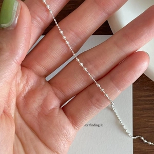 S925 sterling silver minimalist bead chain anklet held by hand for detailed view