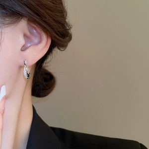 Close-up of silver knot earrings with sparkling cubic zirconia on female model's ear
