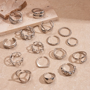 Close-up of 14-piece silver geometric rings set on a textured stone aesthetic background