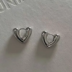 Macro detail of silver heart-shaped hoop earrings with polished mirror finish