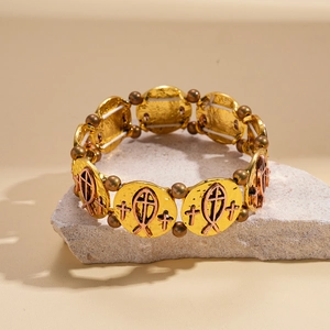 Détail d'un bracelet religieux vintage avec croix et poisson sur support en pierre