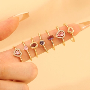 Close-up of seven vintage rings with pink heart and waterdrop zircon stones on fingers
