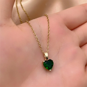 Detailed close-up of a heart-shaped emerald pendant on a classic gold chain