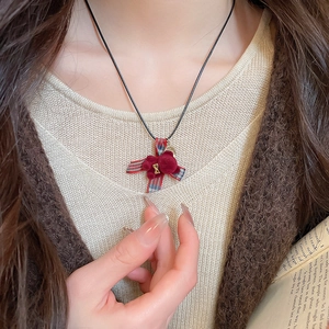 Dettaglio del ciondolo a orsetto rosso con fiocco scozzese e campanellino d'oro su collana
