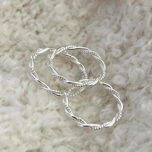 Close-up of three 925 sterling silver twisted rope rings on white faux fur background