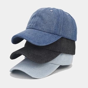 Vertical stack of washed denim baseball caps in dark blue, black, and light blue colors