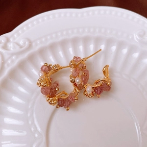 Close-up of 18k gold plated earrings with strawberry crystal and pearls on white tray