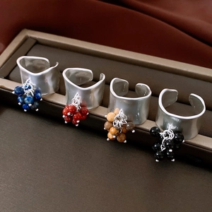 Detail view of adjustable silver rings with colorful beaded charms in a jewelry box