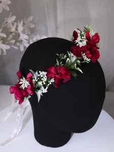 Detail of floral headband with red flowers, green leaves, and pink silk ribbons