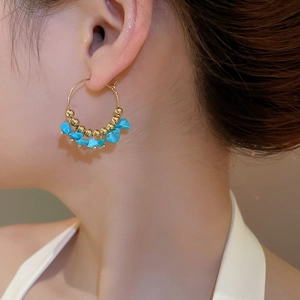 Detail showing bohemian gold hoop earring with turquoise stone chips on female model