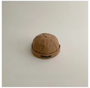 Dettaglio del berretto vintage per bambini con ricamo Unice verde e occhielli metallici