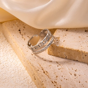 Close-up of double-layered silver ring with chain and twist textures on beige stone