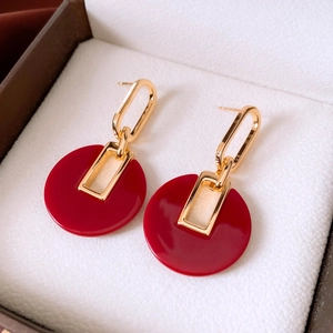 Close-up of red circular drop earrings with 18K gold-plated geometric link design