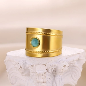 Detailed macro view of vintage gold ring with textured edges and green gemstone inlay