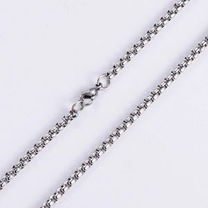 Macro detail of silver stainless steel box chain necklace with a secure lobster clasp