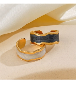 Detailed close-up of vintage wavy gold-plated rings with black and white enamel drip
