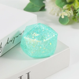 Green crystal maltose stress ball with golden glitter on white books for stress relief