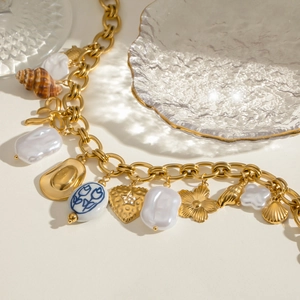 Detailed view of gold chain necklace with baroque pearls and blue tulip ceramic charms