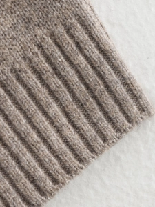 Detailed macro view of high-quality light brown knit texture and ribbed edge detailing