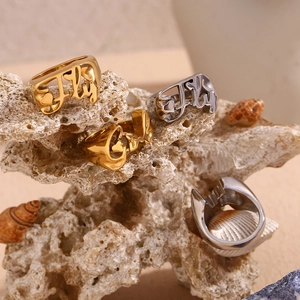Detailed display of gold and silver Fly letter heart rings on coral and seashell decor