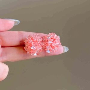 Detail of pink beaded spherical stud earrings held to show texture and size