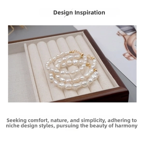 Detail of baroque freshwater pearl bracelet with golden clasp on beige jewelry tray