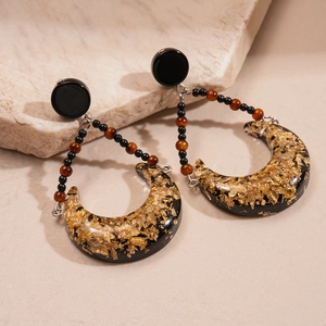 Macro view of bohemian crescent resin earrings with gold foil and beaded chain details