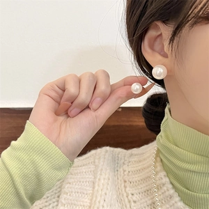Detail of round pearl earrings in various sizes shown on a model for elegant styling