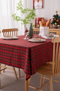 Detail of red festive Christmas plaid tablecloth with gold silk fringe on a dining table