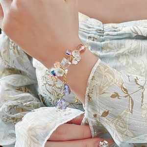 Close-up of colorful crystal flower charm bracelet on wrist with gold metal chain link