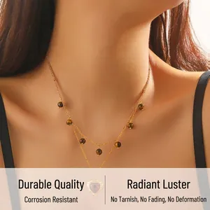 Detail of layered gold chain necklace featuring heart pendant and brown tiger eye beads