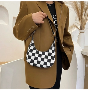 Detail of checkered crescent bag showing smooth texture and slim black shoulder strap