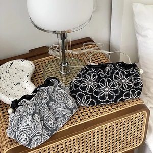Detailed view of embroidered lace handbags with pearl clasps on a rattan bedside table